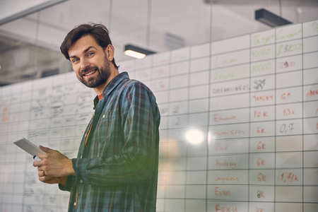 Joyful young man using tablet computer in office