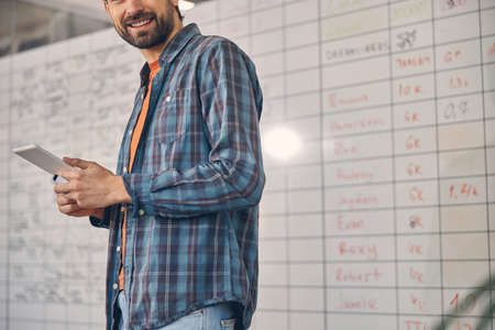 Cheerful male worker with tablet computer standing in office