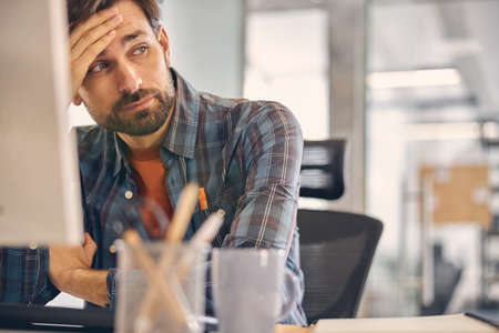 Tired young man sitting at the table in office
