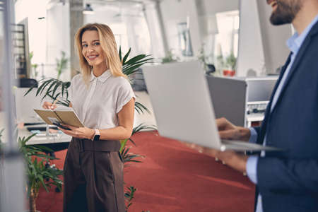 Cheerful young woman writing in notebook at workの写真素材