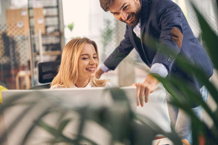 Charming young woman working with male colleague in officeの写真素材