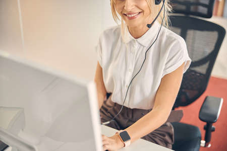 Cheerful female worker using computer in officeの写真素材