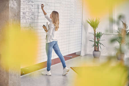 Charming young woman writing on whiteboard in office