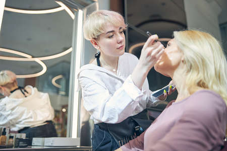 Concentrated young visagiste doing professional aging makeup