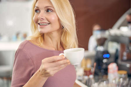 Portrait of pleased woman holding cup of coffee