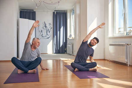 Professional yoga coach stretching with his studentの写真素材