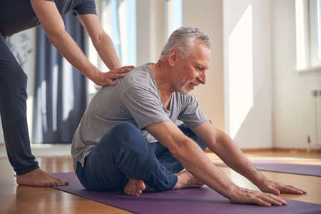 Smiling male performing a basic seated yoga exerciseの写真素材