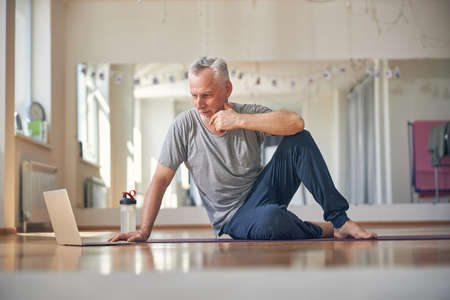 Thoughtful good-looking man sitting on the floorの写真素材
