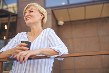 Dreamy woman with coffee and a smartphone