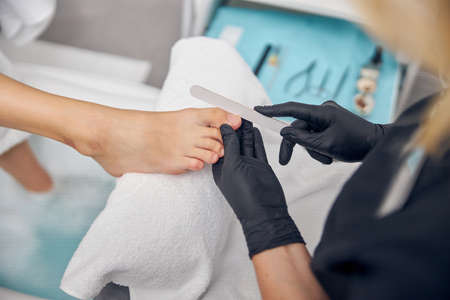 Female nail master doing pedicure for clientの写真素材