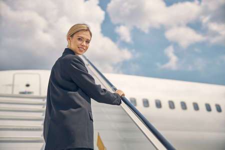 Stylish pretty lady standing on the aircraft steps