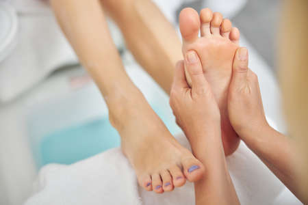 Woman enjoying sole masage by beautician in salonの写真素材