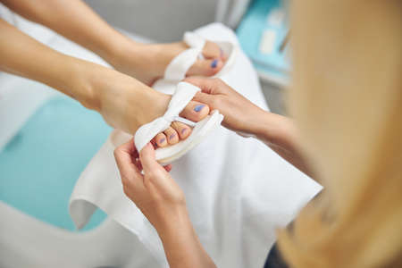 Beautician putting on flip-flops on woman after massageの写真素材