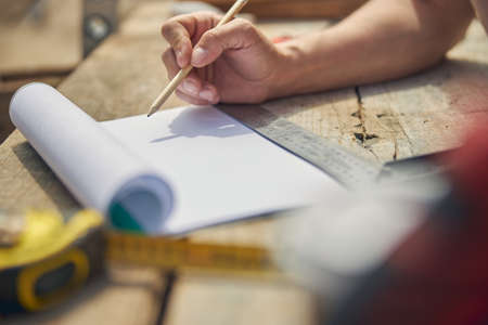 Civil engineer drawing a building plan outdoorsの写真素材