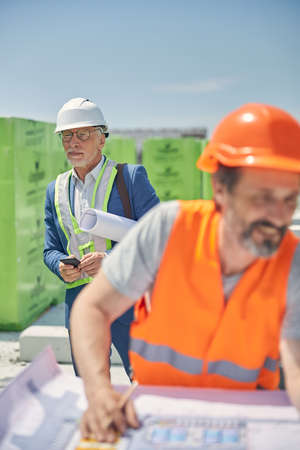 Foreman with a smartphone staring into the distance