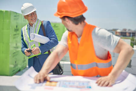 Man with a cellphone looking at a construction worker