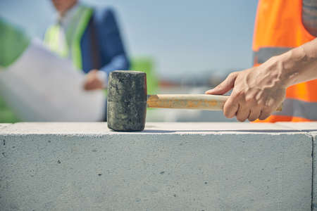 Male worker hand clutching a brick hammer