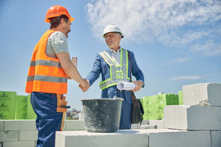 Pleased construction manager shaking a builder hand