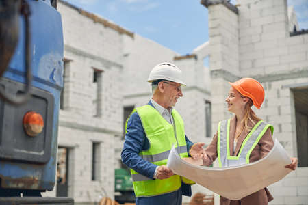 Male worker and a merry woman holding a drawing together