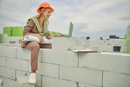 Pleased woman with drawings sitting on the bricksの写真素材