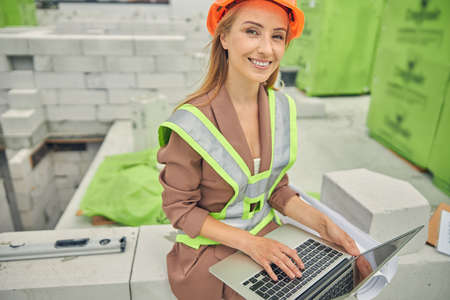 Happy pretty woman in a reflective vest sitting outsideの写真素材