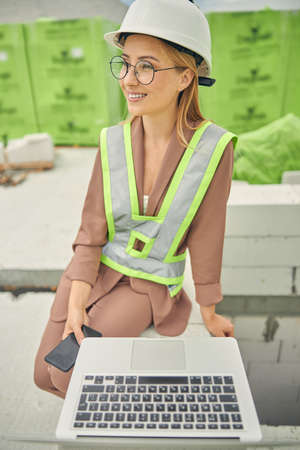 Smiling pleased lady with a phone looking away