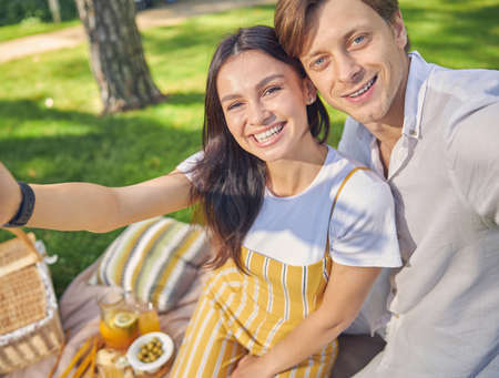 Happy smiling woman and male sitting in the green park