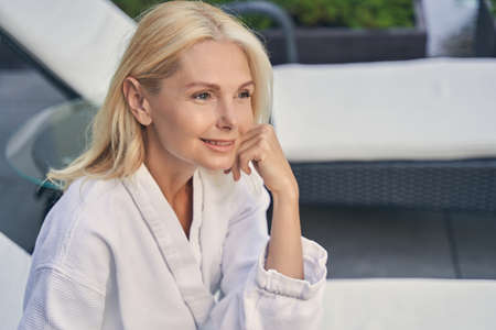 Smiling woman is wearing soft white bathrobe