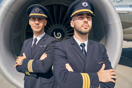 Two Caucasian airmen standing by the aircraft
