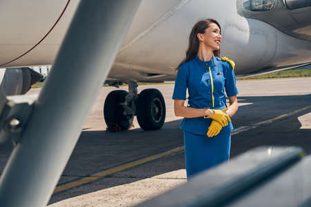 Joyous slim lady standing at the aircraftの写真素材