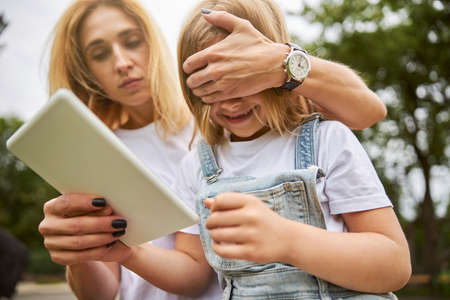 Seriously female putting hand on eyes of little girlの写真素材