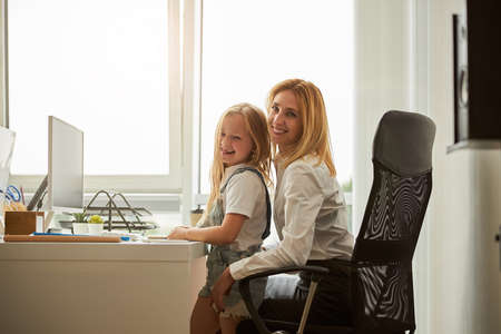 Laughing mother with beautiful daughter spending time at the computer in indoorsの写真素材