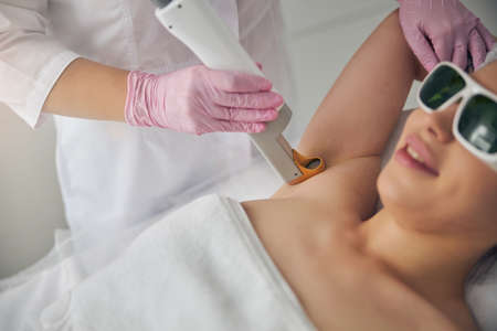 Cosmetician removing her female patient underarm hairの写真素材
