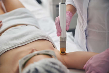 Doctor in latex gloves using a laser device