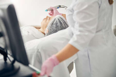 Female doctor treating a woman using a beauty machine
