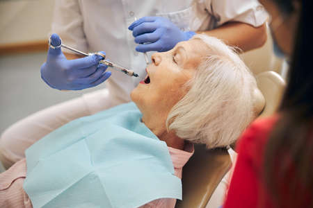 Doctor making injection to female visitor in dental clinicの写真素材