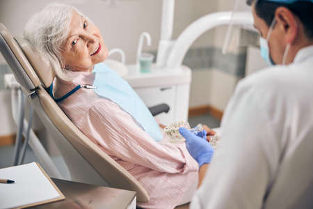Mature male dentist working with his elderly patientの写真素材