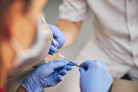 Hands of doctor and assistant while working with professional tools