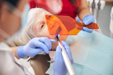 Dentist is using ultraviolet curing light toolの写真素材
