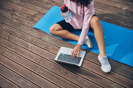 Sporty woman spending time with computer on yoga matの写真素材