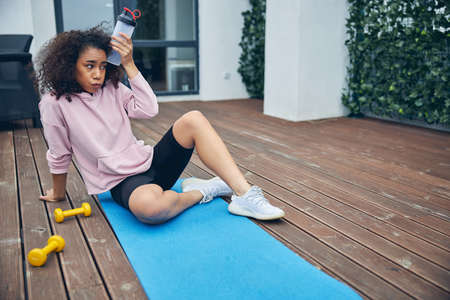 Beautiful woman with curly hair relaxing after trainingの写真素材