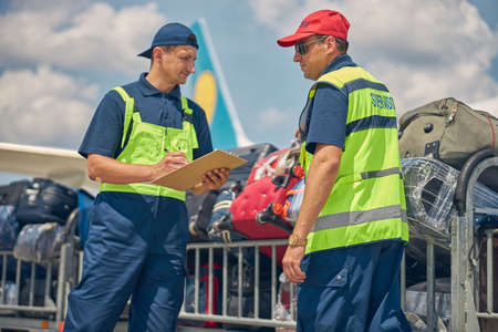 Airport workers preparing for unloading customer luggageの写真素材