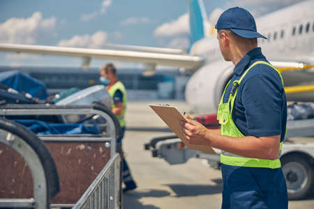 Man looking at a working baggage handlerの素材 [FY310157624150]