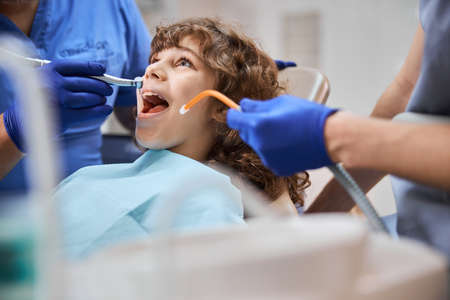 Adorable kid having his teeth treated by a dentist