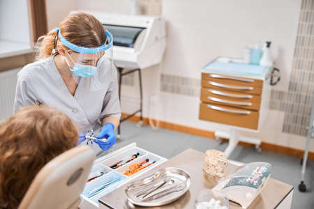 Young woman holding a syringe in dentists office