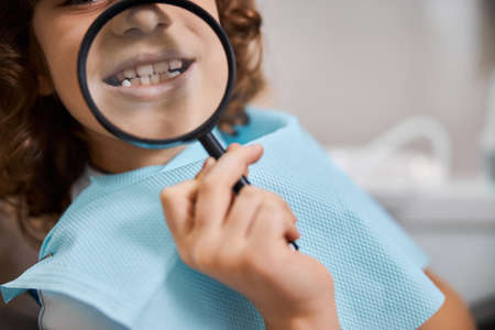 Kid in a dental clinic playing with a magnifying glassの写真素材