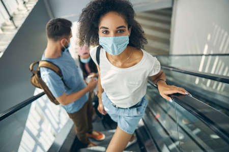Cute African female in protective mask going to the gate for traveling by planeの写真素材