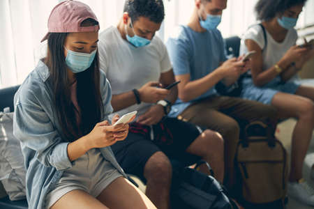 Good looking woman in pink cap surfing internet while waiting for catch a flight