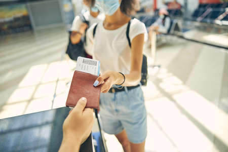 Happy woman handing over passport in airportの写真素材