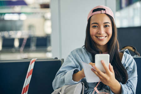 Stylish young lady in denim jacket styling message on modern smartphoneの写真素材